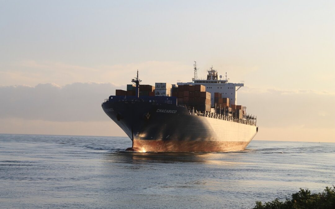 A cargo ship sailing over blue water at sunset 