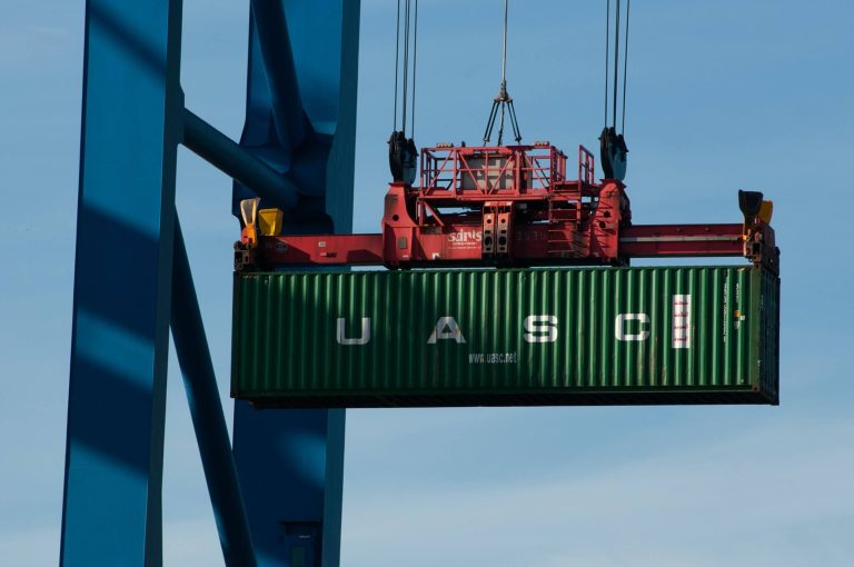 A single shipping container suspended from a crane; the contents could be eligible for duty drawback under certain circumstances.