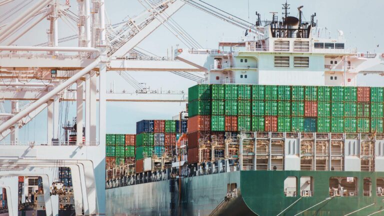 Cargo ship loaded with containers at a port terminal representing tariffs and taxes in international logistics and global supply chains.