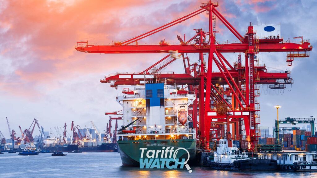 Container ship docked at a busy cargo port beneath large red container cranes at sunset, with the "Tariff Watch" logo overlaid on the bow. The image represents international trade, global supply chains, shipping, customs compliance, and tariff developments affecting importers.